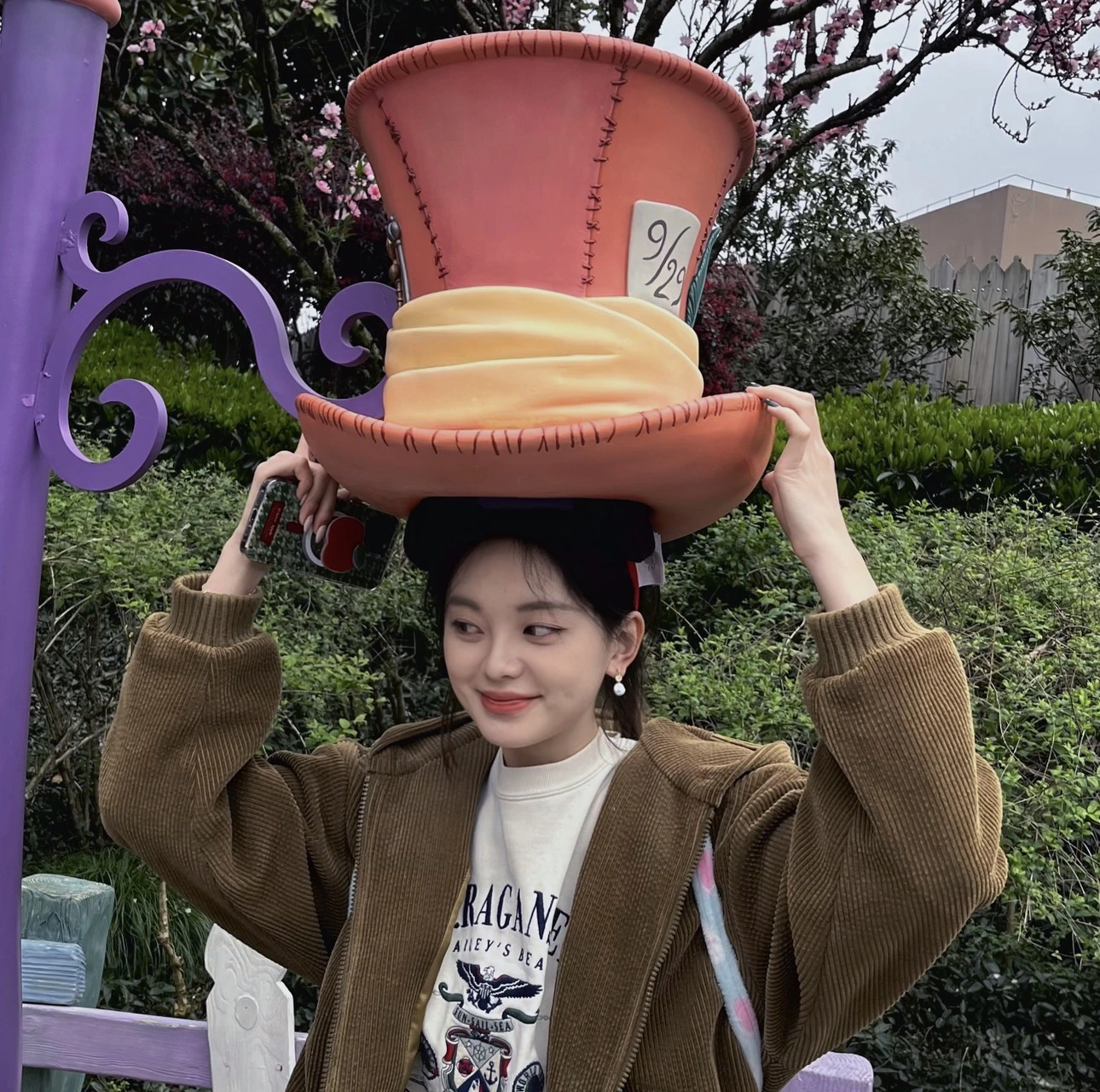 Ziyu holding an oversized hat in a garden.